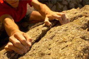 uomo con mani sulla roccia fa arrampicata sportiva in abruzzo