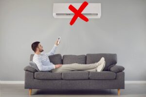 uomo sul divano con condizionatore e x rossa