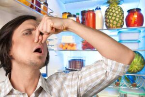 signore che si tappa il naso davanti al frigo