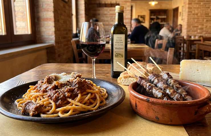 Piatto di maccheroni alla chitarra e arrosticini abruzzesi in una trattoria tipica di Penne con olio extravergine d'oliva Vestino.