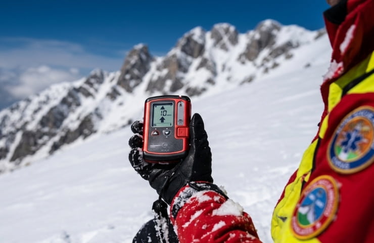 Soccorritore alpino in Abruzzo controlla dispositivo ARVA sul Gran Sasso innevato, aprile 2026.