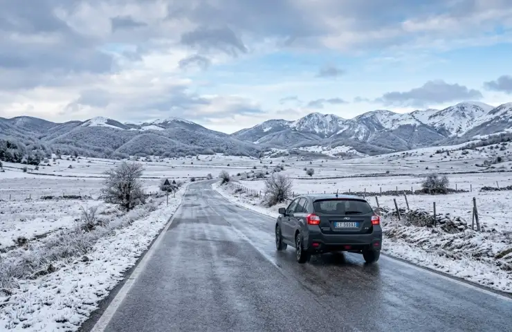 Auto percorre una strada statale innevata e bagnata tra le montagne dell'Abruzzo durante la gelata di aprile.
