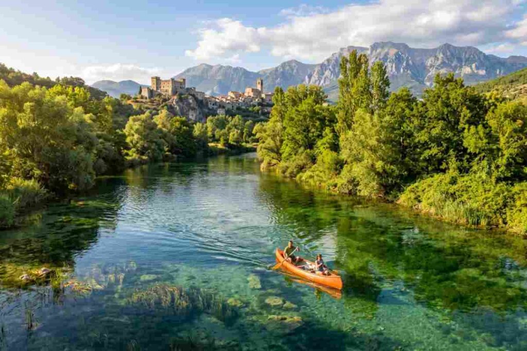 Canoa sul fiume Tirino con vista panoramica sul borgo e Castello Piccolomini di Capestrano in Abruzzo.