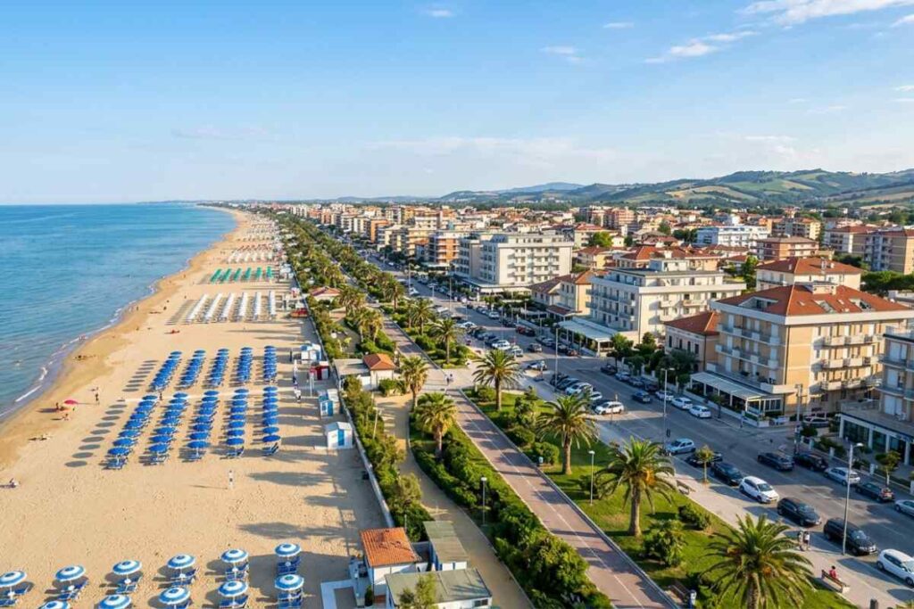 Veduta aerea del lungomare di Alba Adriatica in Abruzzo con la spiaggia, il mare Adriatico e gli edifici della città sotto un cielo sereno.