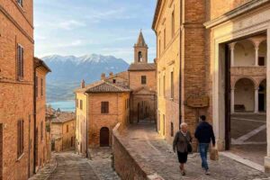 Vicolo storico di Penne in Abruzzo con palazzi in mattoni rossi al tramonto e vista sul Gran Sasso e il Lago di Penne.