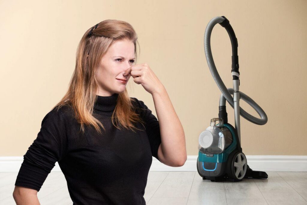 donna che si tappa il naso per il cattivo odore che esce dall'aspirapolvere