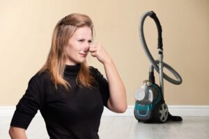 donna che si tappa il naso per il cattivo odore che esce dall'aspirapolvere